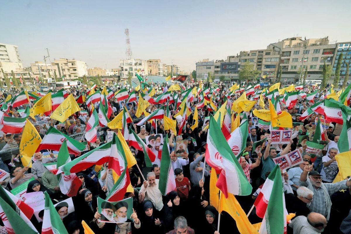 Warga Iran mengibarkan bendera nasional dan meneriakkan slogan-slogan saat merayakan gencatan senjata antara Iran dan Israel di Enghlab Square di ibu kota Teheran pada Selasa (24/6/2025).(AFP/ATTA KENARE)